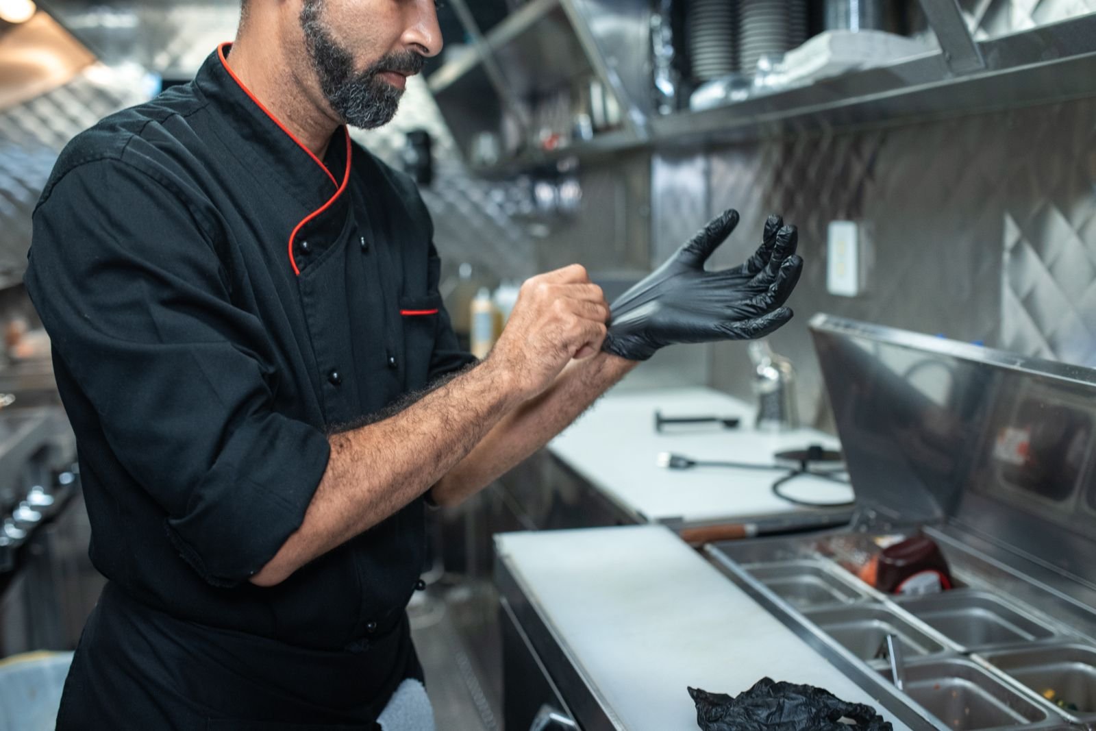 Food service worker putting on gloves before preparing food